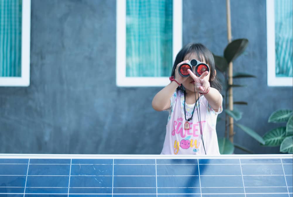Une petite fille est devant un panneaux solaire