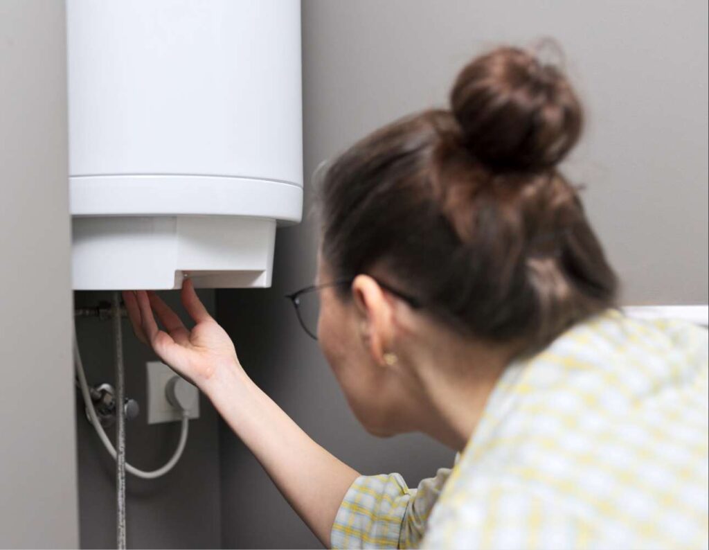 Une femme règle son chauffe-eau électrique