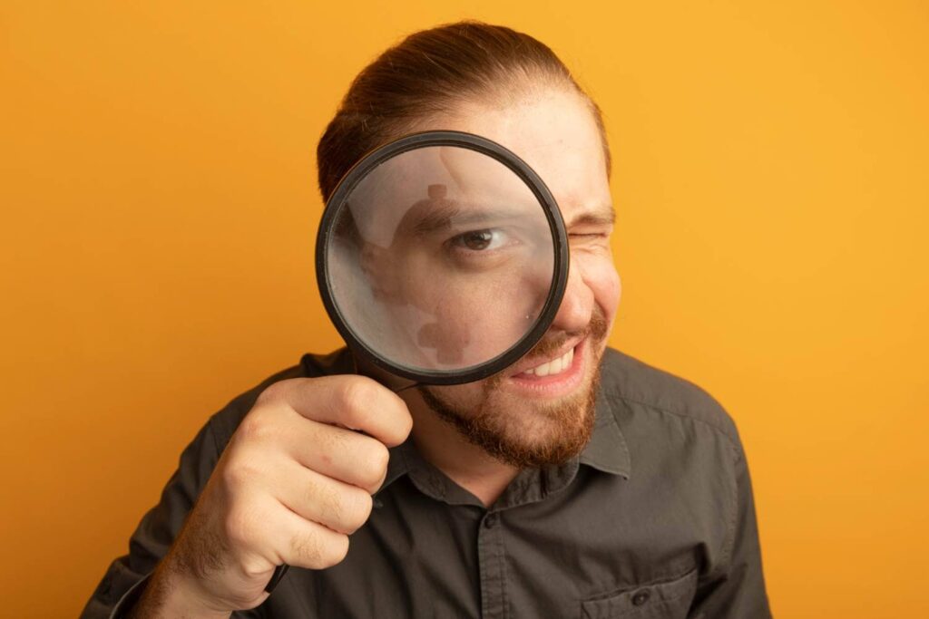 Un homme analyse son compteur d'énergie à la loupe.