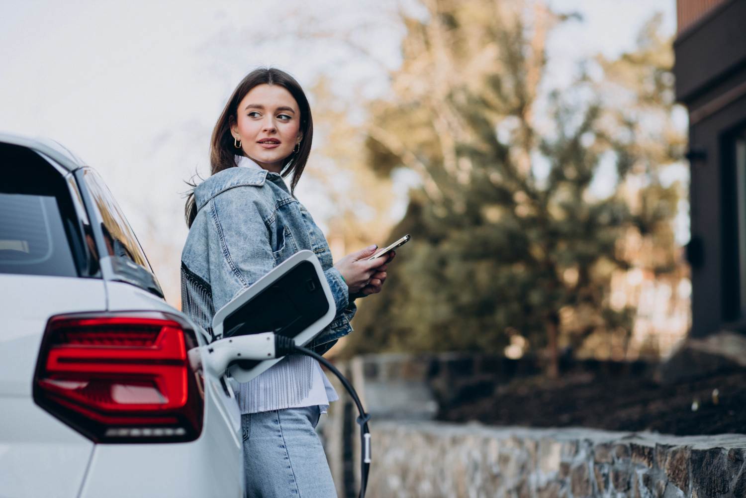 Une jeune femme charge sa voiture électrique